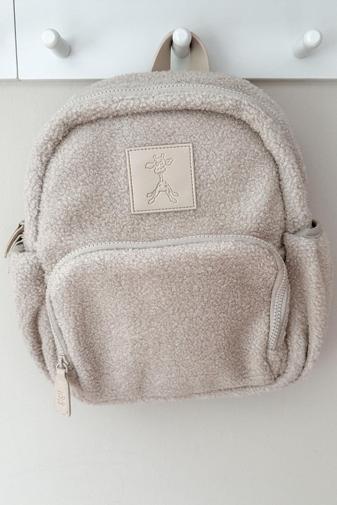 Kids Ava teddy fleece backpack in sand beige hanging on a hook 