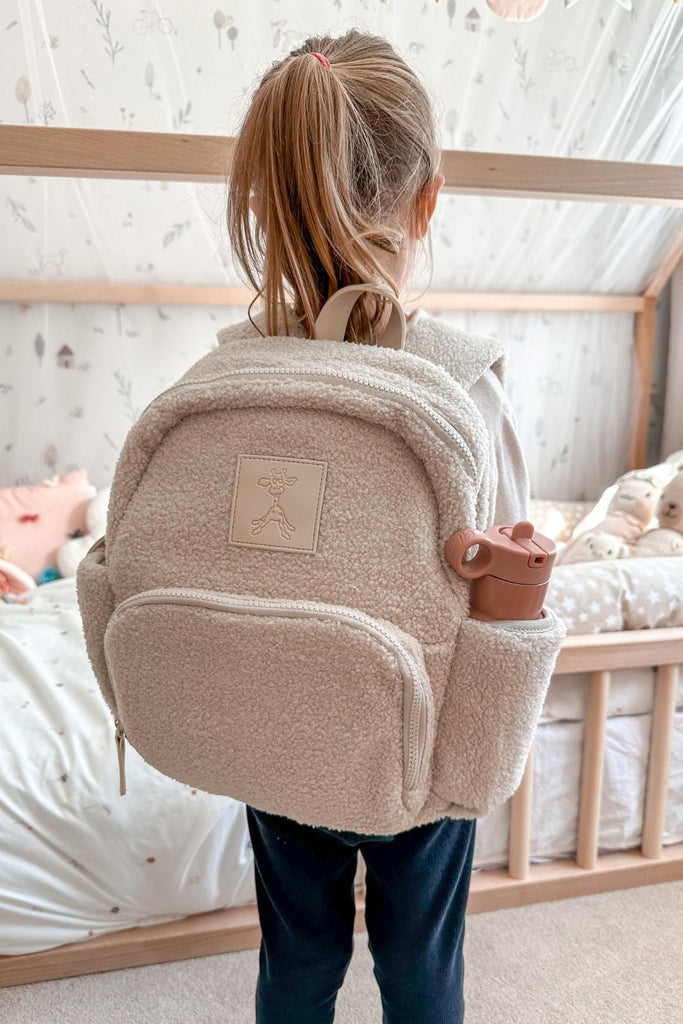 Child wearing the Ava sand beige kids teddy backpack with water bottle in side pocket 