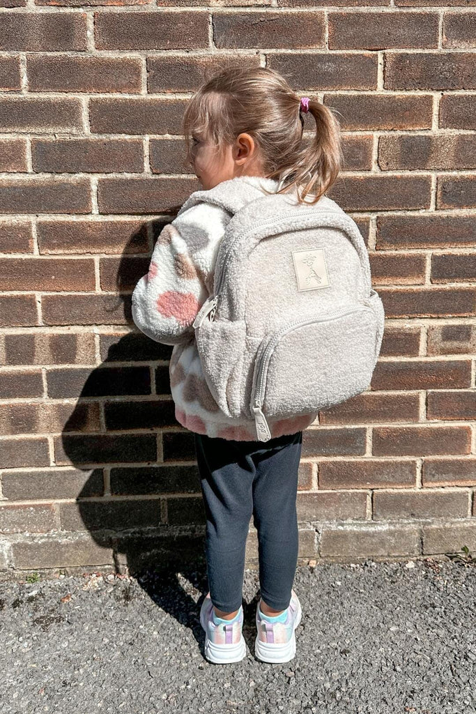 Child wearing the Ava kids teddy backpack in sand beige 