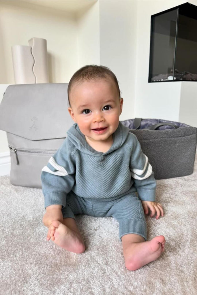 Baby with grey vegan leather baby changing backpack with grey eddy nappy caddy