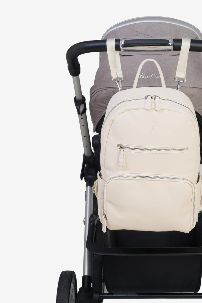 Beige vegan leather diaper backpack hanging on a pram with matching pram clips 