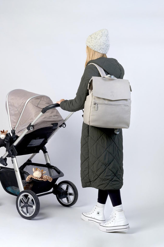 Mum wearing the grey vegan leather diaper backpack whilst pushing pram 