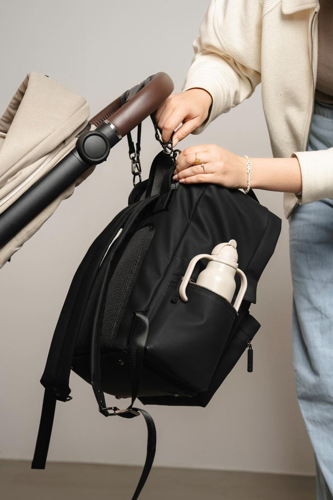 Model clipping the Coast Backpack onto the buggy with the pram straps.