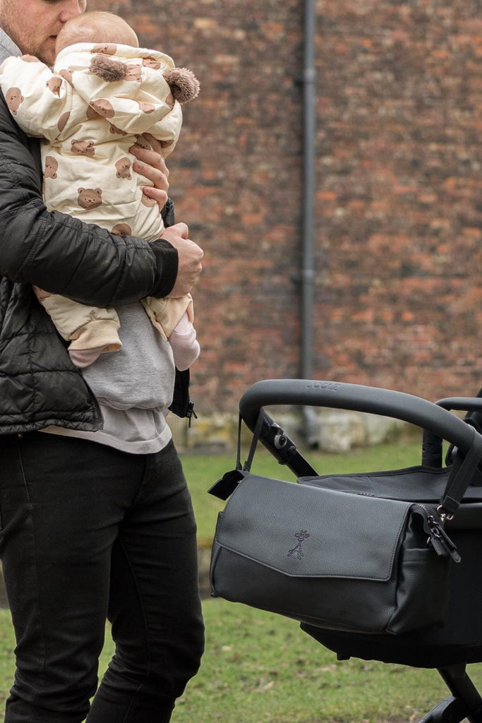 Dad holding baby with the Ebba (2.0) - Jet Black Buggy Organiser attached to the pram for easy access of essentials.