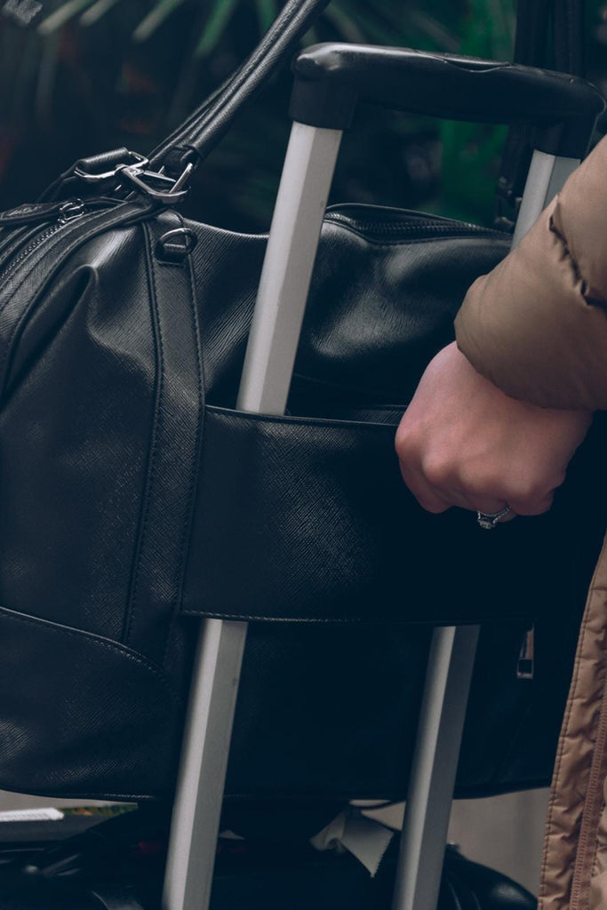 Black vegan leather changing bag with trolley sleeve on a suitcase 