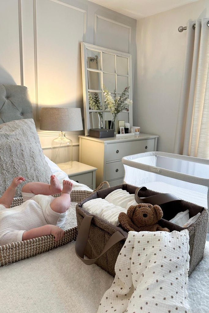 Brown teddy fleece diaper caddy next to baby on a bed 