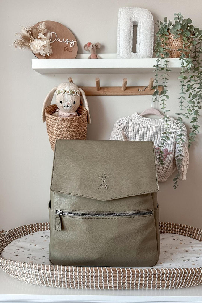 Olive green diaper backpack with zipped front pocket in a nursery 
