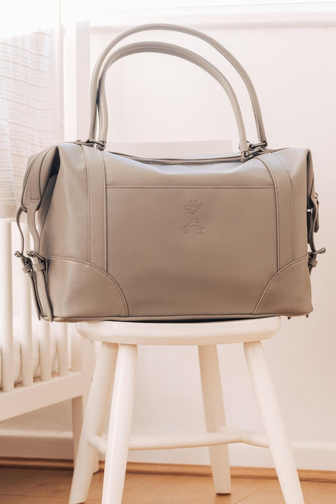 Grey vegan leather diaper bag in a nursery