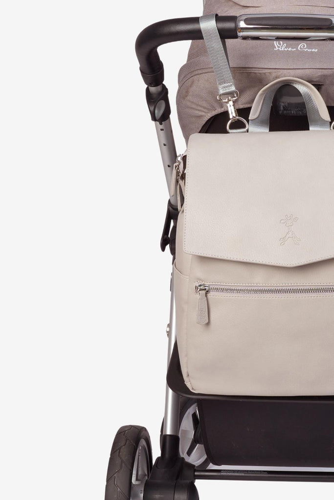 Grey vegan leather diaper backpack hanging from pram with matching pram clips