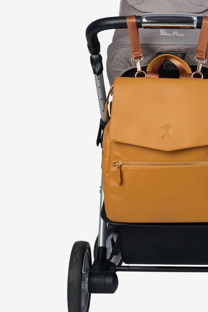 Tan vegan leather diaper backpack attached to pram with matching pram clips
