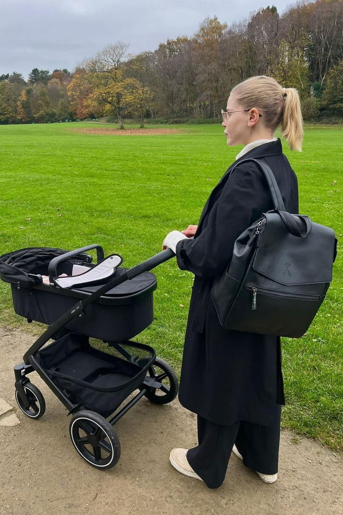 Mum out with baby wearing the black vegan leather diaper backpack 