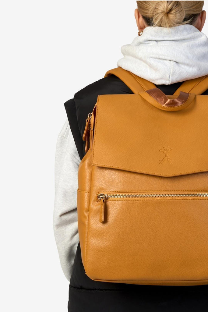 Mum wearing tan vegan leather changing backpack with front zipped pocket and giraffe gigil logo 