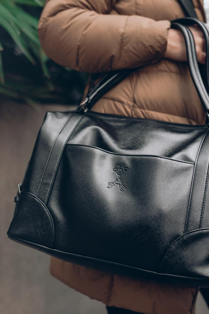 Mum holding the vegan leather black changing bag with giraffe logo 