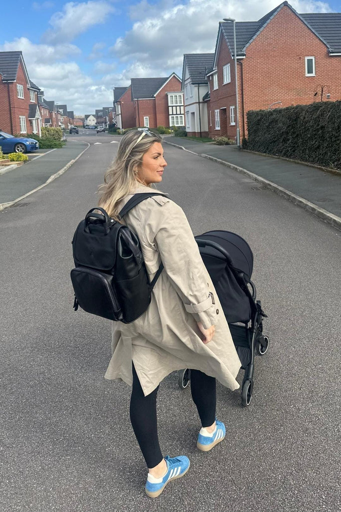 Mum pushing pram wearing black vegan leather diaper backpack 