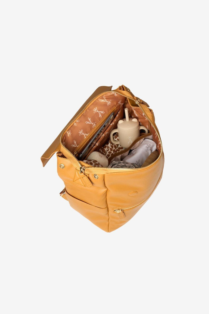 Tan vegan leather diaper backpack with matching giraffe interior lining filled with essentials 